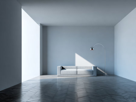 A spacious room features light gray walls and a simple gray couch. A tall floor lamp stands beside the couch, creating soft shadows from the morning sunlight coming through large windows.の素材