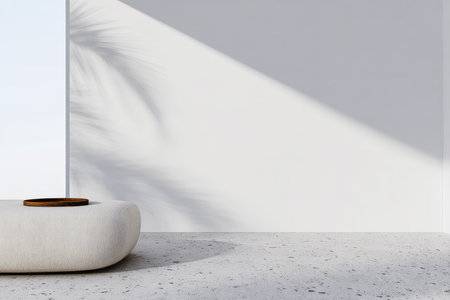 A minimalistic room showcases a plush, off-white seating area against a bright wall. Natural light streams in, casting interesting shadows from a nearby plant, creating a calming ambiance.の素材
