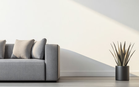 A cozy living room showcases a gray couch adorned with light-colored pillows. A minimalistic plant in a black pot sits nearby, illuminated by soft afternoon light.の素材
