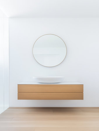 This bathroom showcases a sleek, minimalist style with a floating wooden vanity, a round mirror, and a simple wash basin, providing a spacious and bright atmosphere.の素材