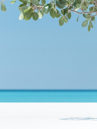 A serene tropical beach showcases soft white sand and turquoise water. Gentle waves lap at the shore under a clear blue sky, with green leaves providing shade.の素材