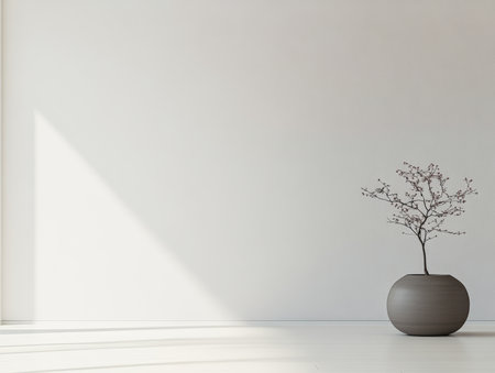 A spacious, bright room features a simple, round gray pot holding a delicate branch. The sunlight streams in, creating soft shadows on the clean floor and wall.の素材