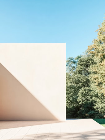 A sleek white wall casts a sharp shadow on a smooth surface, highlighting the minimalist design. Lush greenery surrounds the structure, creating a peaceful atmosphere in daylight.の素材