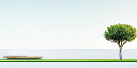 A green tree stands next to a wooden bench on a well-maintained grassy area. The scene is peaceful, under a blue sky with minimal clouds, creating a calm atmosphere.の素材