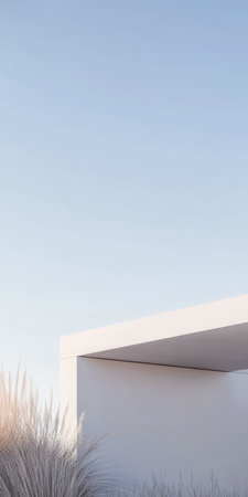 A clean and minimalist structure blends with nature, featuring a simple, angular design. Soft grasses surround the building, enhancing its calm atmosphere in bright daylight.の素材