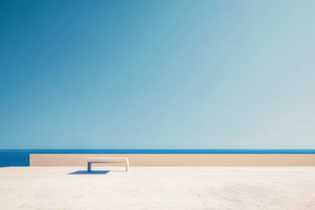 A minimalist bench sits on a light-colored surface overlooking a calm ocean. The clear blue sky creates a peaceful atmosphere ideal for relaxation and contemplation.の素材