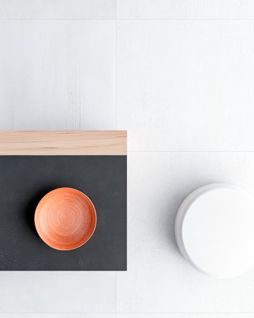 A clean and minimalistic tabletop scene features an orange bowl centered on a dark surface. A white round object sits to the right, contributing to the stylish design.の素材