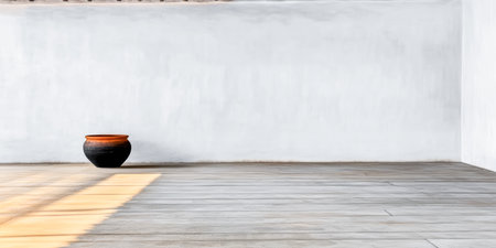 A bright interior space showcases a traditional black pot with an orange rim sitting on smooth, light-colored flooring. It emphasizes minimalism and natural light during the day.の素材