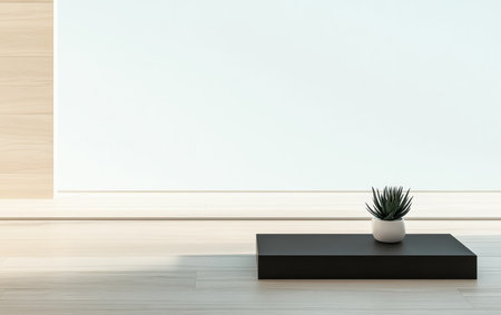 A small green plant sits in a white pot on a dark platform in a bright, minimalist room. The light wall enhances the calming atmosphere of the space.の素材