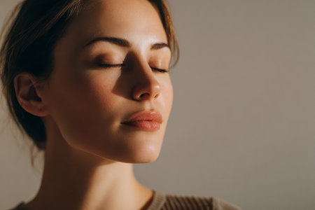 A young woman enjoys a moment of peace and relaxation in her tranquil home environment, with her eyes closed and a gentle expression on her face.の素材