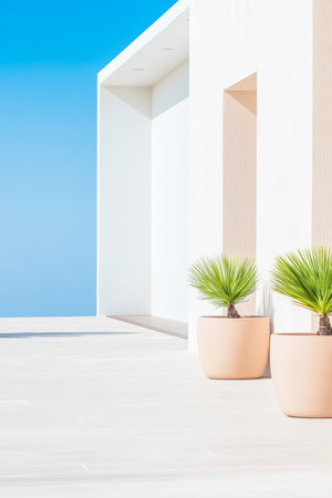 Modern architecture features smooth white walls and two potted green plants under a bright blue sky. This relaxing scene is perfect for warm summer days by the coast.の素材