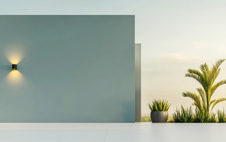 This serene outdoor area features a minimalist blue wall, stylish lighting, and lush plants. The warm glow of sunset highlights the beauty of nature in this tranquil setting.の素材
