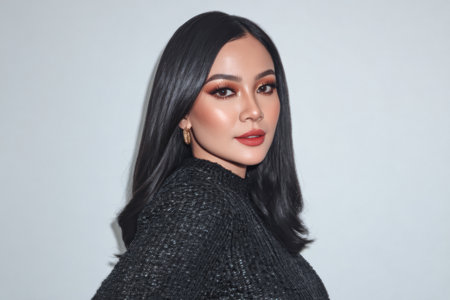 Woman with long black hair showcases a confident pose, wearing a chic black outfit. Her makeup features bold eye shadow and a bright lip color, highlighting her features.の素材