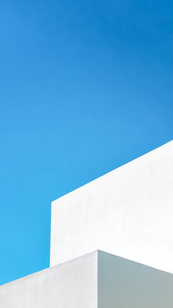 Tall white structures stand against a bright blue sky. The clean lines and angles of the buildings create a striking contrast. Light reflects off the surfaces, highlighting their shapes.の素材