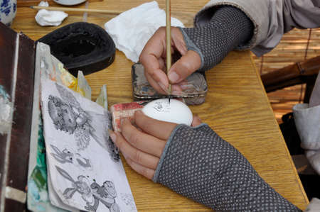 Painting an egg. An artisan painting micro-designs on an egg, here in Cheng Du, Chinaのeditorial素材