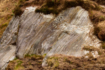 Colourful layered rock eroded by centuries of weather and climatic conditions found here in the countryside of Scotland, Gt. Britainの写真素材