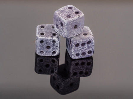 Three dice on a black reflective surface. Isolated on a black background.の写真素材
