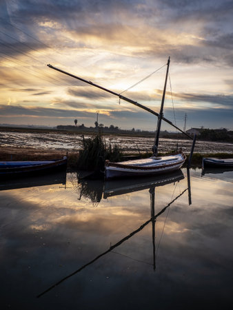 Fishing boats at low tide in the estuary at sunset.の写真素材