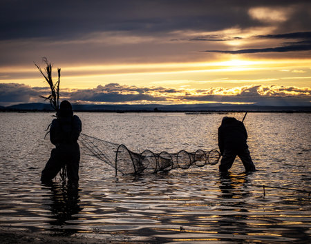 Silhouette of Fishermen with fishing net in the lake.
