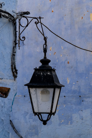 Old street lamp on blue wall in Chefchaouen, Moroccoの写真素材