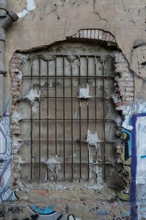 Old window with rusty bars and graffiti on the wall of an abandoned buildingの写真素材
