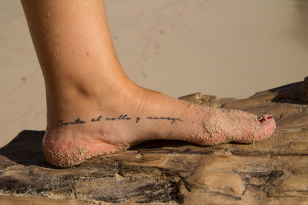 Female feet on a piece of wood with a tattoo on them.の写真素材