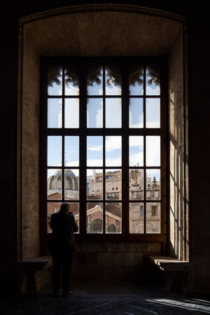 A man looking through the window of a palace in Bologna, Italyの写真素材