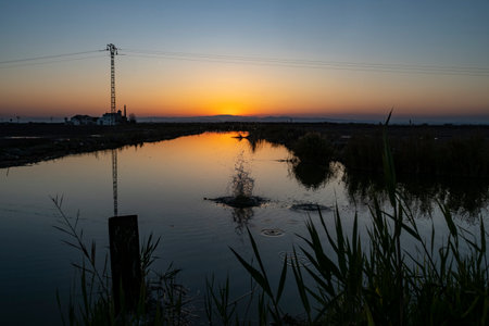 Sunset over a small river in the Netherlands. The sun is reflected in the water.の写真素材