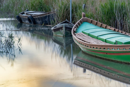 Boats in a lake at sunset, with reflection in waterの写真素材