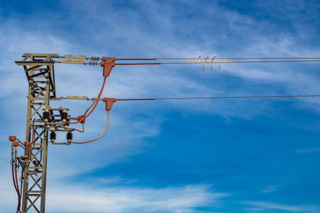 High voltage electric pole with blue sky and white clouds in the background