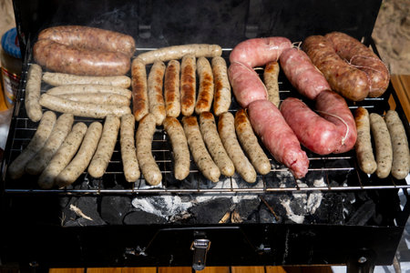 Grilling sausages on barbecue grill with smoke. Food backgroundの写真素材