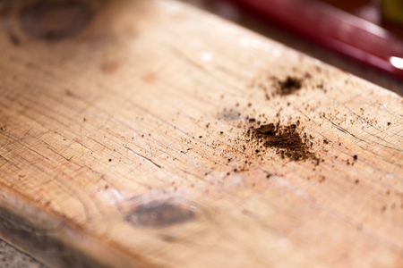 An abstract close up of coffee grinds spilled on a rustic timber cafe bench top with shallow depth of field and space for text or content.の写真素材
