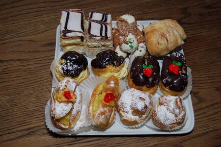 Fresh baked Italian and French Pastries on a white dish and wood tableの写真素材