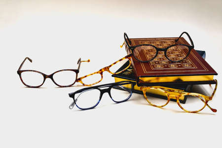 Assorted, stylish eyeglasses next to leatherbound books with gilded edgedの写真素材