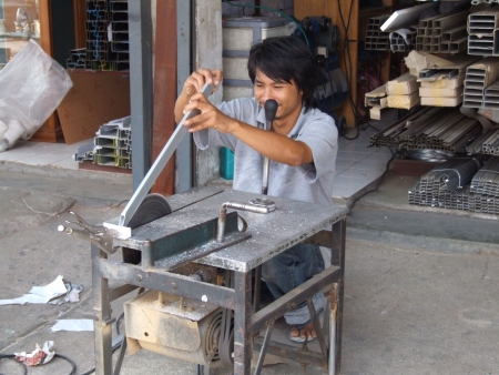 BANGKOK, THAILAND - OCTOBER 28: Thai man cuts metal outside a construction material shop October 28, 2005 in Bangkok. のeditorial素材