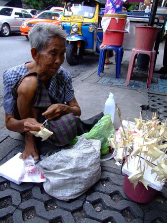 BANGKOK, THAILAND - MAY 20: Thai elderly woman sells paper fish on sticks on the street on May 20, 2008 in Bangkok. のeditorial素材