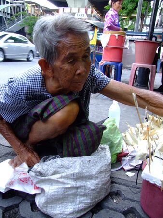 BANGKOK, THAILAND - MAY 20: Thai elderly woman sells paper fish on sticks on the street on May 20, 2008 in Bangkok. のeditorial素材