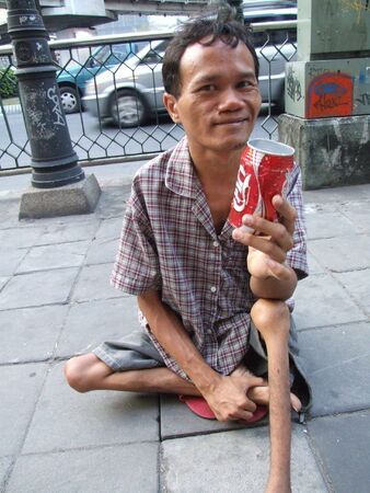 BANGKOK, THAILAND - SEPTEMBER 23: Thai crippled man sits on a path in central Bangkok begging for...