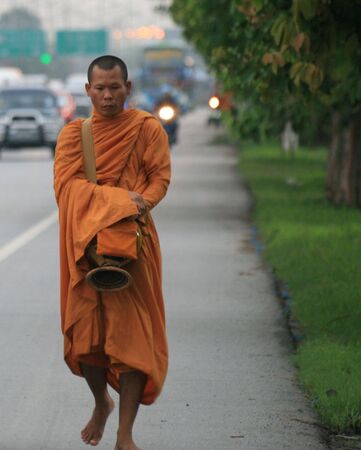 BANGKOK, THAILAND - MAY 18: Buddhist monk walks down the roadside at dawn to collect offerings on May 18, 2009 in Bangkok. のeditorial素材
