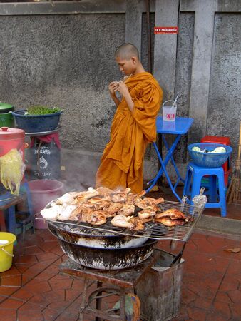 BANGKOK, THAILAND - JULY 26: Thai Buddhist monk stands behind a barbecue on Khaosarn road. July 26 2005 in Bangkok. のeditorial素材