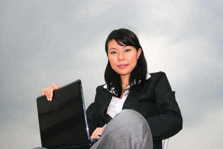 Asian business woman outdoors on a laptop.の写真素材