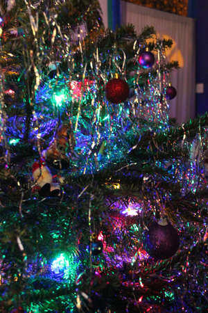 Fat, bushy Christmas Tree decorated in traditional manner with bright lights, baubles and tinsel.の写真素材
