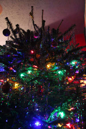Fat, bushy Christmas Tree decorated in traditional manner with bright lights, baubles and tinsel.の写真素材