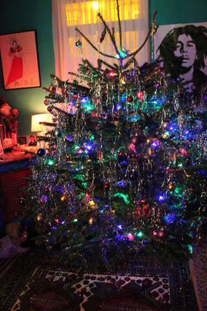 Fat, bushy Christmas Tree decorated in traditional manner with bright lights, baubles and tinsel.の写真素材