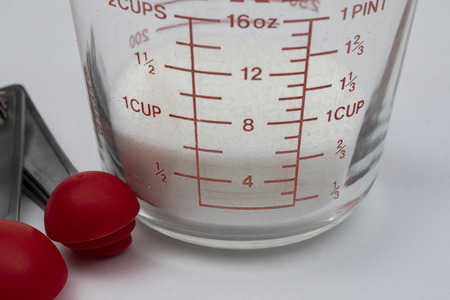 White cane sugar in a measuring cup with measuring spoons.の写真素材