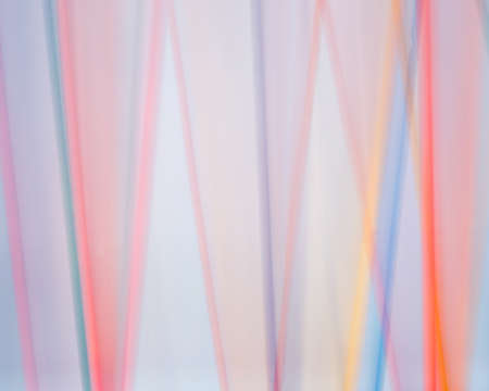 Colored dowels blurred against a white background in a time lapse photo.の写真素材