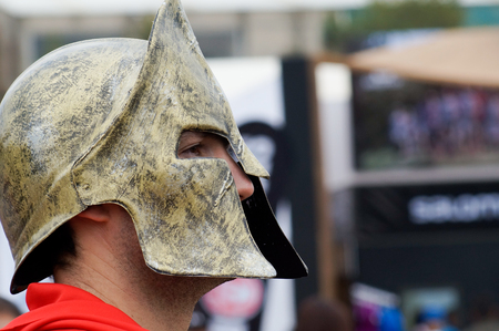 Male Spartan Race host smiling  wearing a gold spartan helmet and red capeのeditorial素材