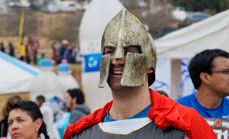 Male Spartan Race host smiling  wearing a gold spartan helmet and red capeのeditorial素材