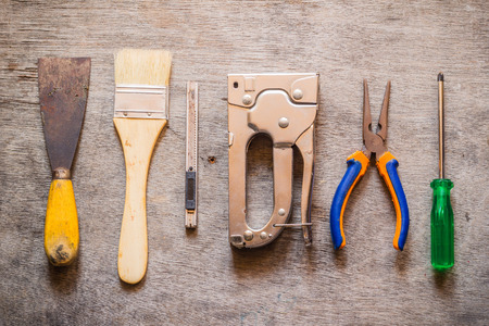 Brush, trowel, cutter, stapler, pliers and screwdriver on wooden tableの写真素材