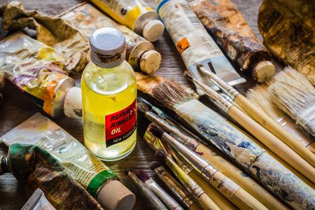 Rinseed oil, paintbrushes and oil paints on wooden tableの写真素材